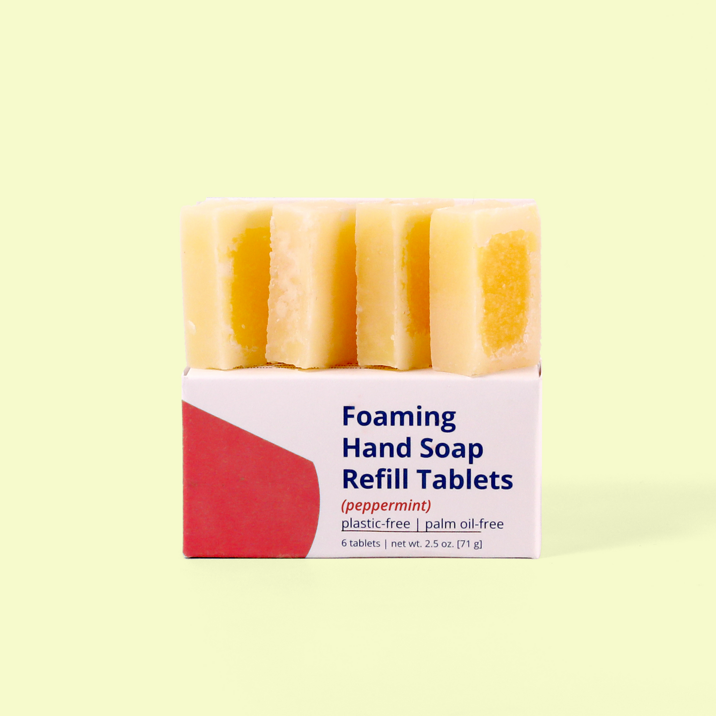 Six peach-colored soap tablet bars stacked on a white and red packaged box labeled 'Foaming Hand Soap Refill Tablets (peppermint)' that indicates it's plastic-free and palm oil-free, containing 6 tablets with net weight 2.5 oz (71 g), photographed against a pale yellow background
