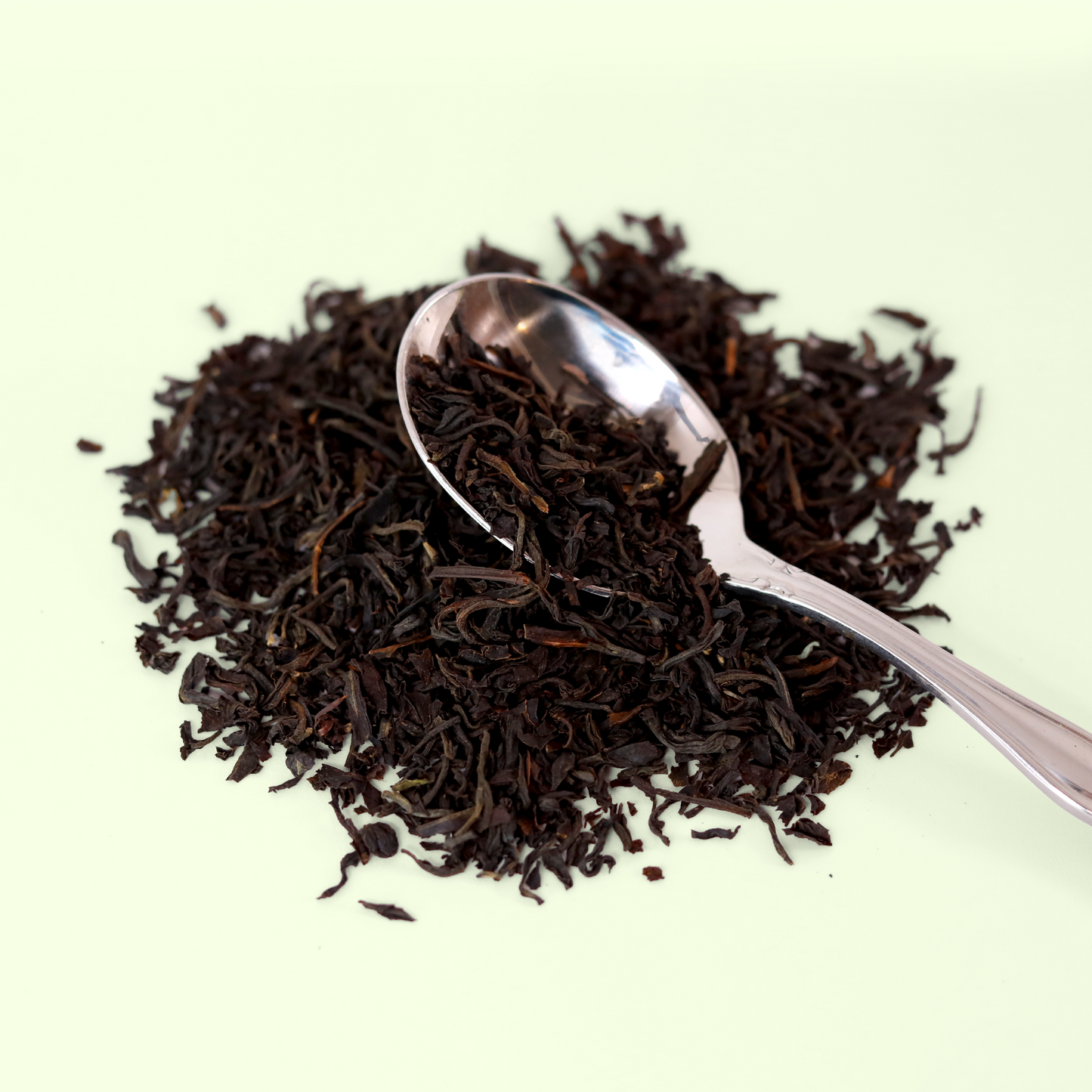 A close-up view of a pile of dried Bright Star Breakfast Blend tea leaves. A metal spoon is visible, scooping up some of the tea blend. A Good Store product.