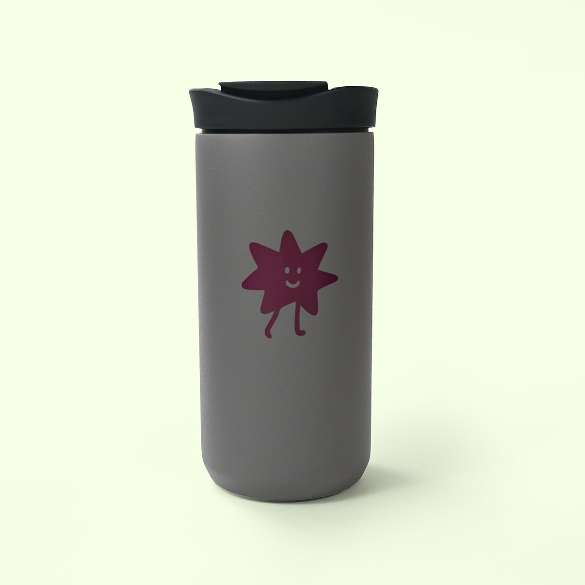 Gray travel mug with a purple smiling star design on a beige background