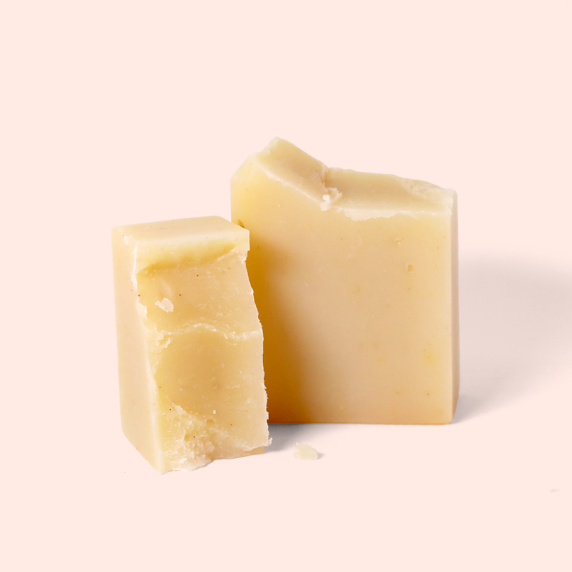 A pale yellow soap blocks broken in half on a light pink background. Both have a smooth texture with slight imperfections on cut edges. Sun Basin Soap - Good Store.