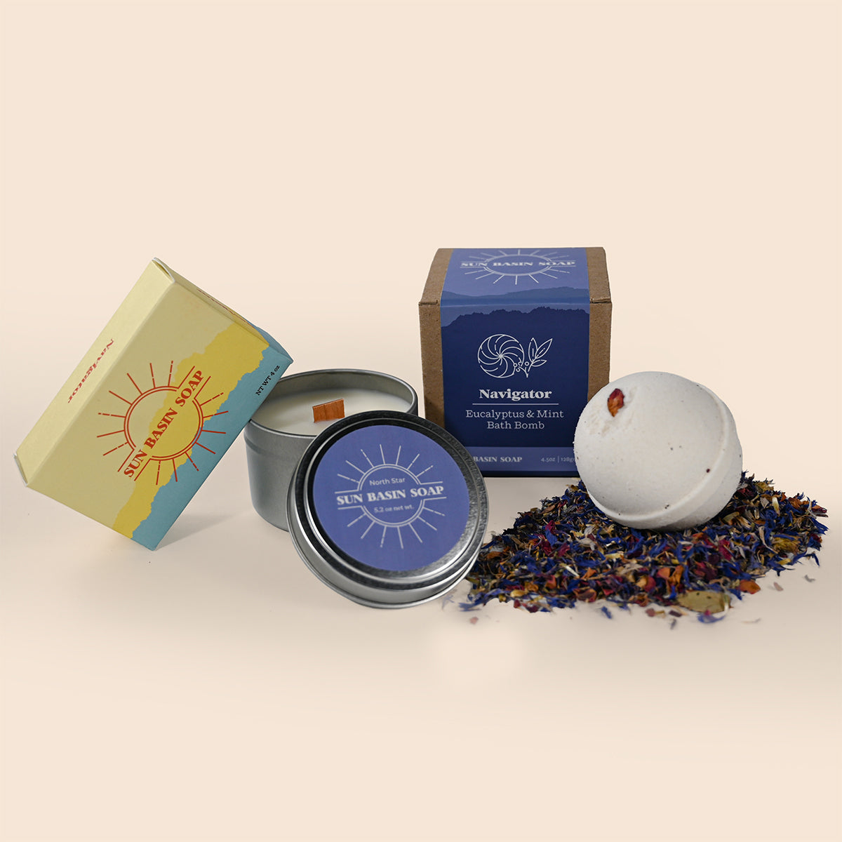 Collection of bath products including a candle, soap, and bath bomb on a beige background