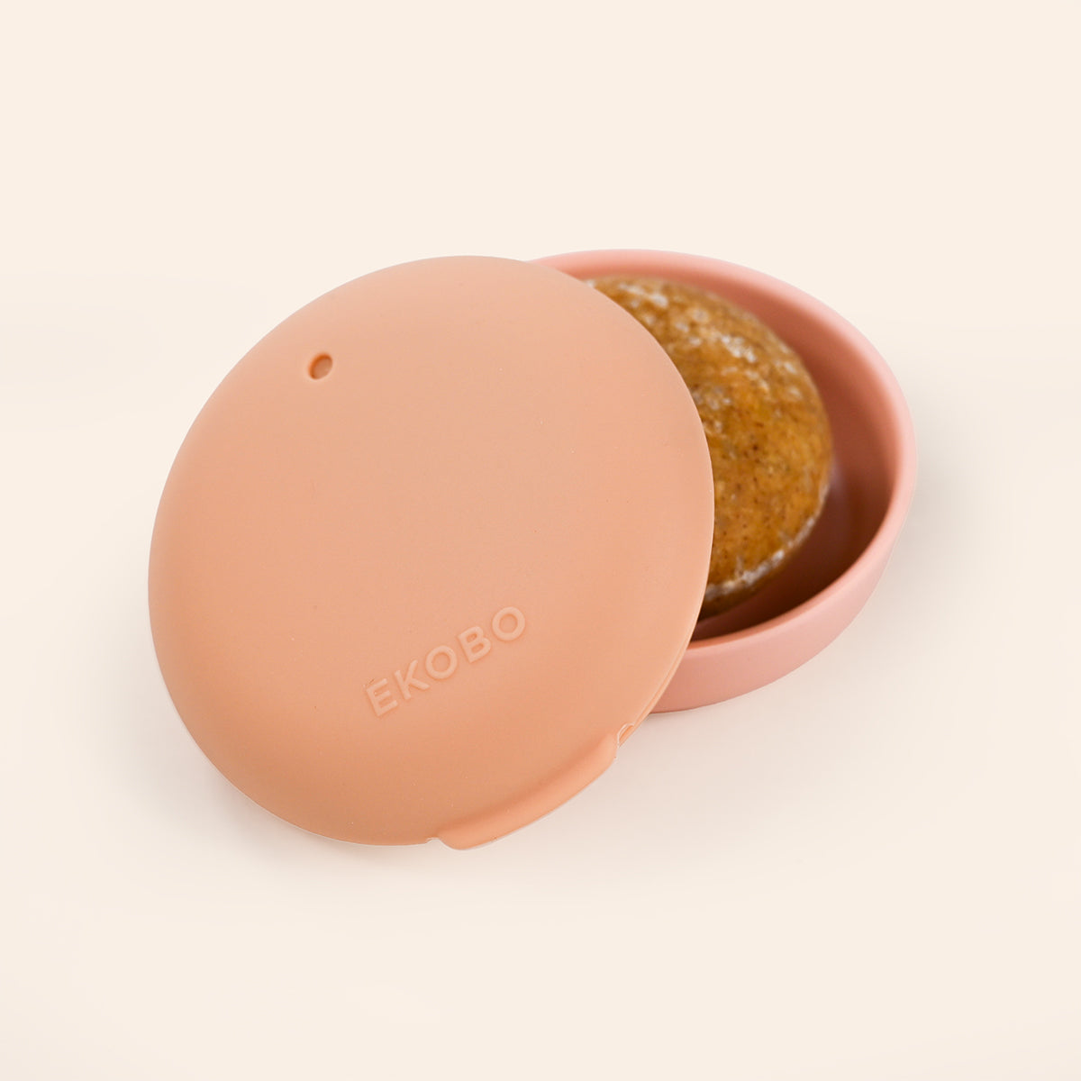 Pink shampoo bar travel case with a lid featuring the brand 'Ekobo' on a beige background