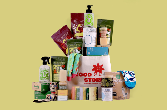 Image of a pile of Good Store products displayed in front of a green background. Some products include Sun Basin Soap bars, Keats & Co coffee and tea, Awesome socks, and more