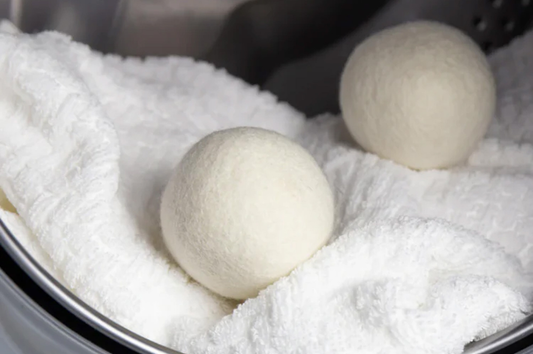 Image of two dryer balls in a dryer on top of a fluffy white blanket or towel