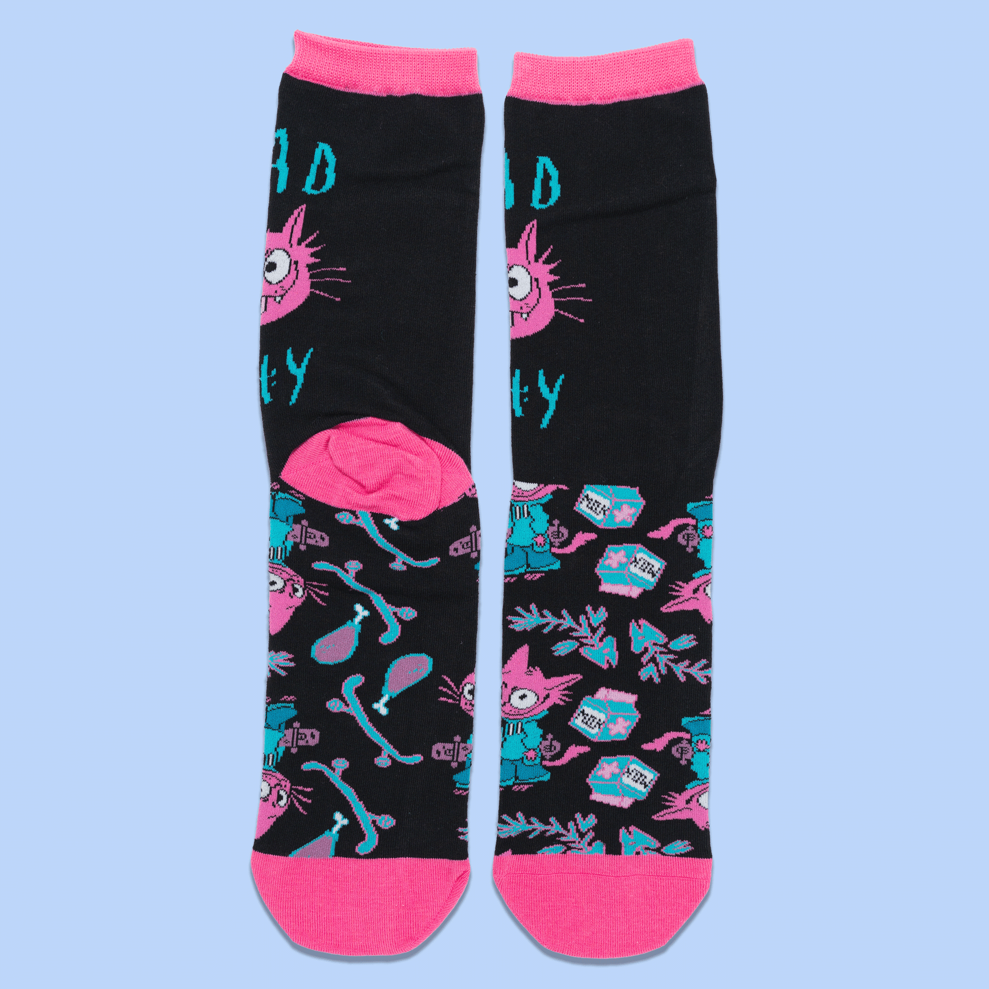 A pair of black crew socks with bright pink toes, heels, and cuffs, featuring a colorful cartoon cat and teal text and pattern details, displayed against a light blue background.