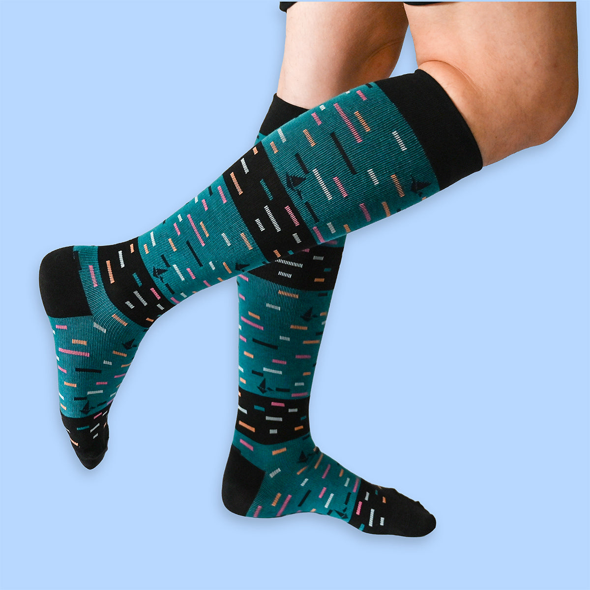 Teal and black patterned socks worn by a person on a light blue background