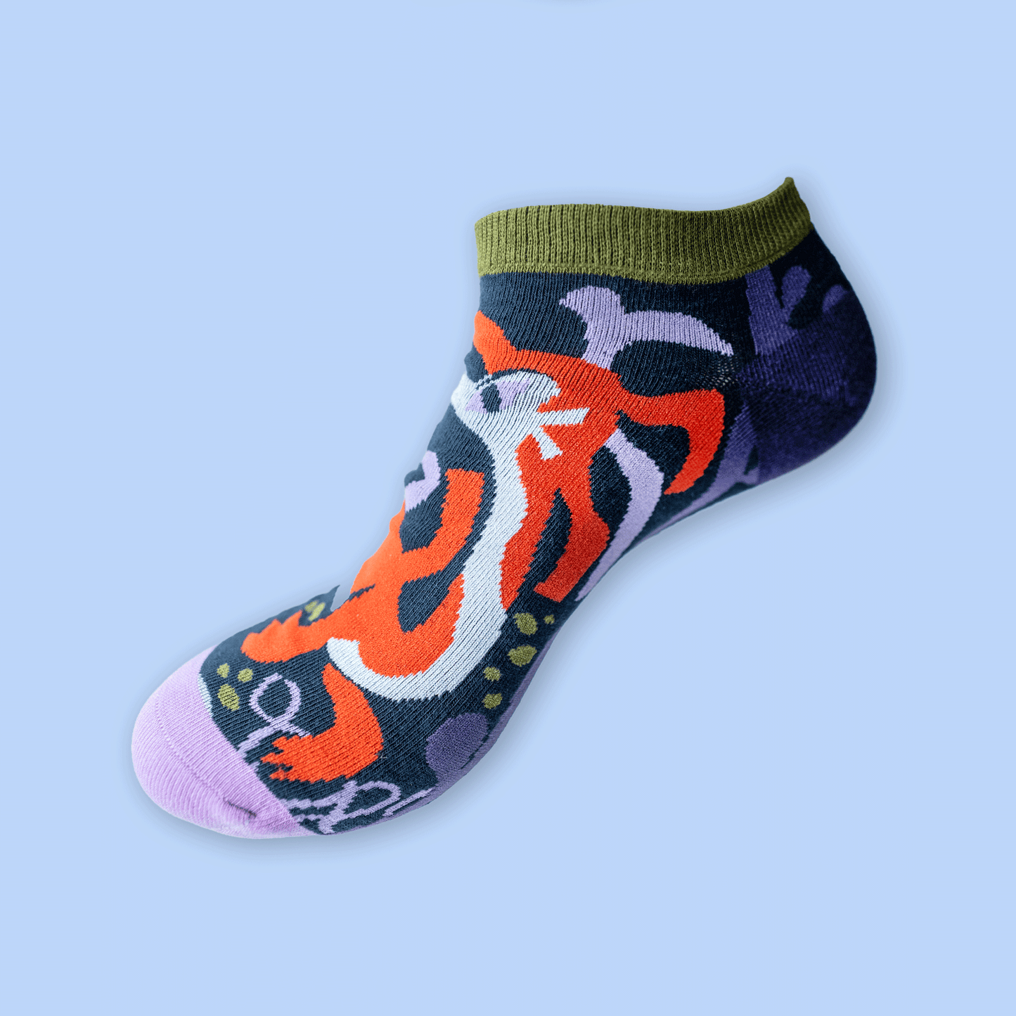 A single low-cut ankle sock with a colorful abstract pattern, featuring an olive green ribbed cuff, a dark navy base, orange, white, and purple graphic details, and a light purple toe, shown against a solid light blue background.