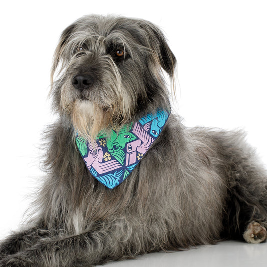 A gray shaggy dog lying down wearing a colorful patterned bandana around its neck, photographed against a clean white background.