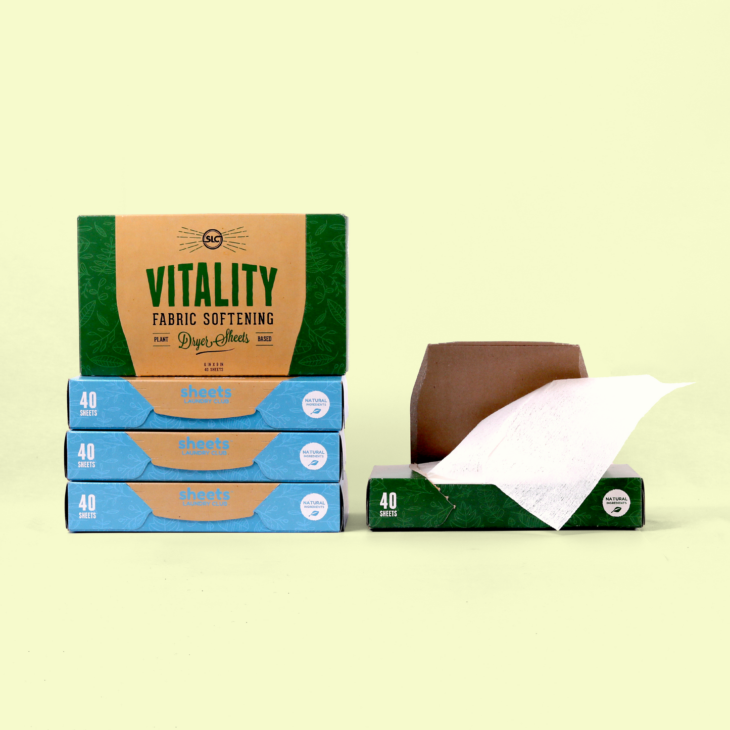 An arrangement of eco-friendly dryer sheet products from Sheets Laundry Club. The display includes a green "VITALITY" fabric softening dryer sheets box on top of three stacked blue boxes each containing 40 sheets. To the right is an open green box with a white dryer sheet partially pulled out, showing the product's texture. Dryer sheets from EcoGeek a Good Store product.