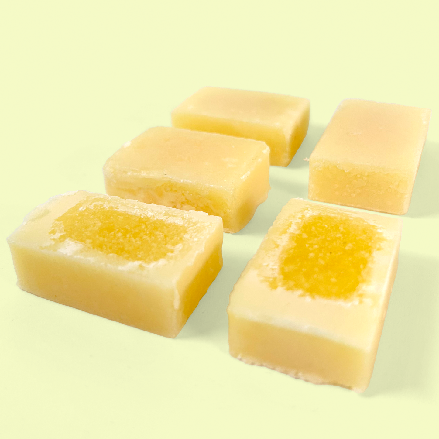 Five individual soap refill tablets arranged in a grid pattern against a pale yellow background. Each rectangular tablet has a cream-colored outer edge with a more intense yellow center, showing the distinct two-tone design of these concentrated soap tablets. Foaming hand soap refill tablets from EcoGeek a Good Store product. 