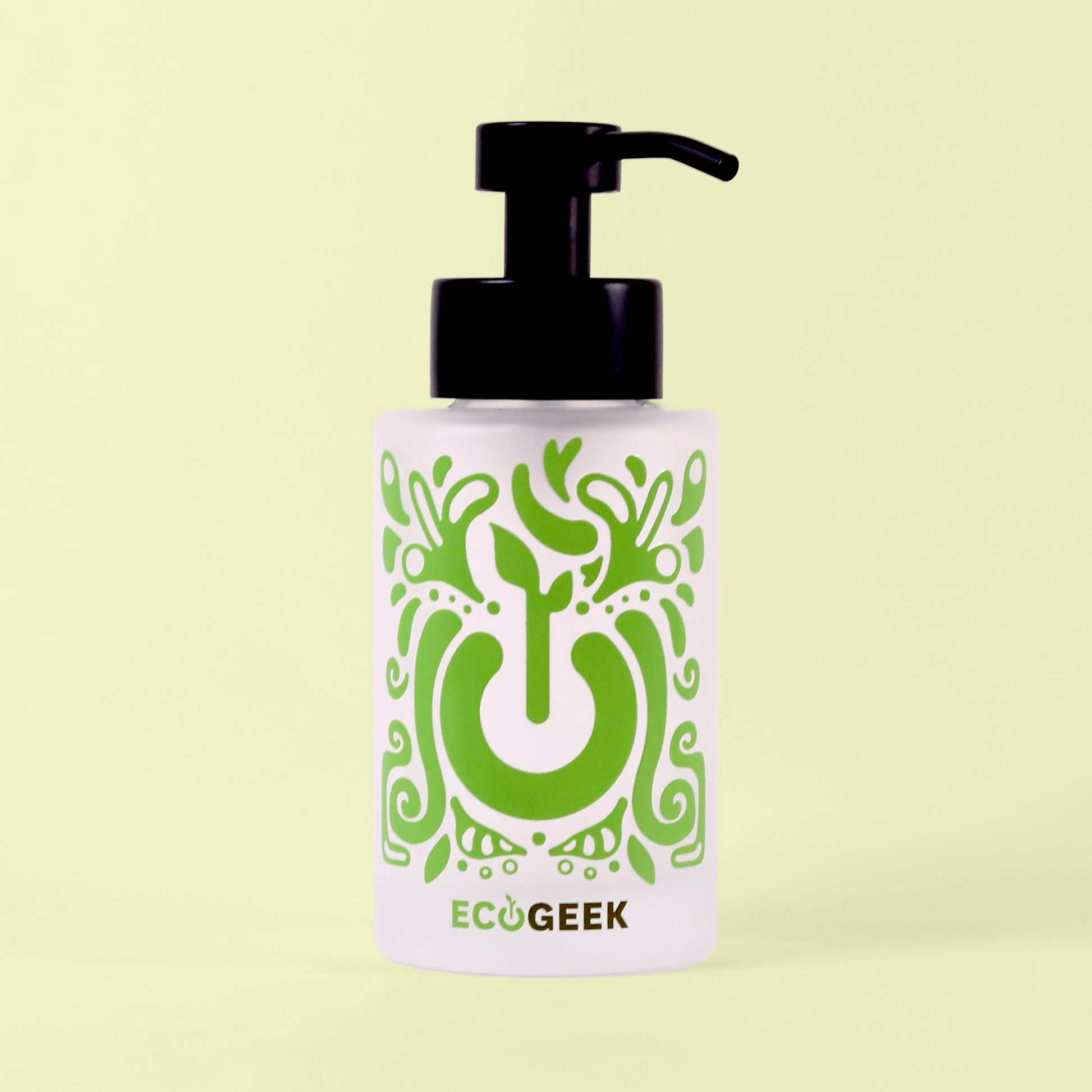 A glass pump bottle with a black dispenser top featuring a decorative green pattern with a power button symbol integrated into the design. The bottle is labeled "ECOGEEK" at the bottom and is photographed against a pale yellow background. Foaming hand soap bottle from EcoGeek a Good Store product.