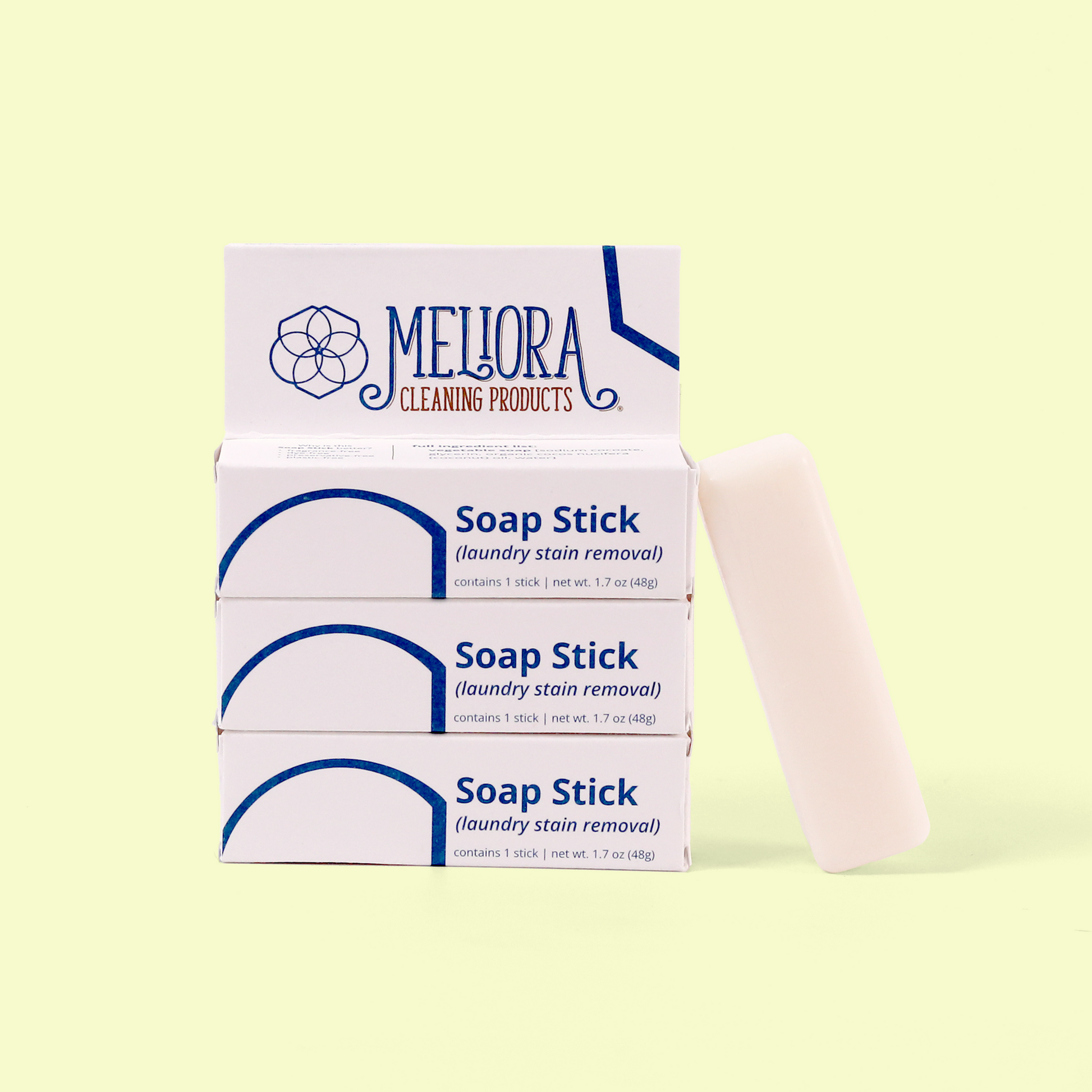 Three stacked Meliora Soap Stick boxes for laundry stain removal displayed with a white soap stick standing beside them against a pale yellow background. Each box is labeled with the Meliora logo and "Soap Stick (laundry stain removal)" in blue text. Each package contains one stick weighing 1.7 oz (48g). Soap stick laundry stain remover from EcoGeek and Good Store product.