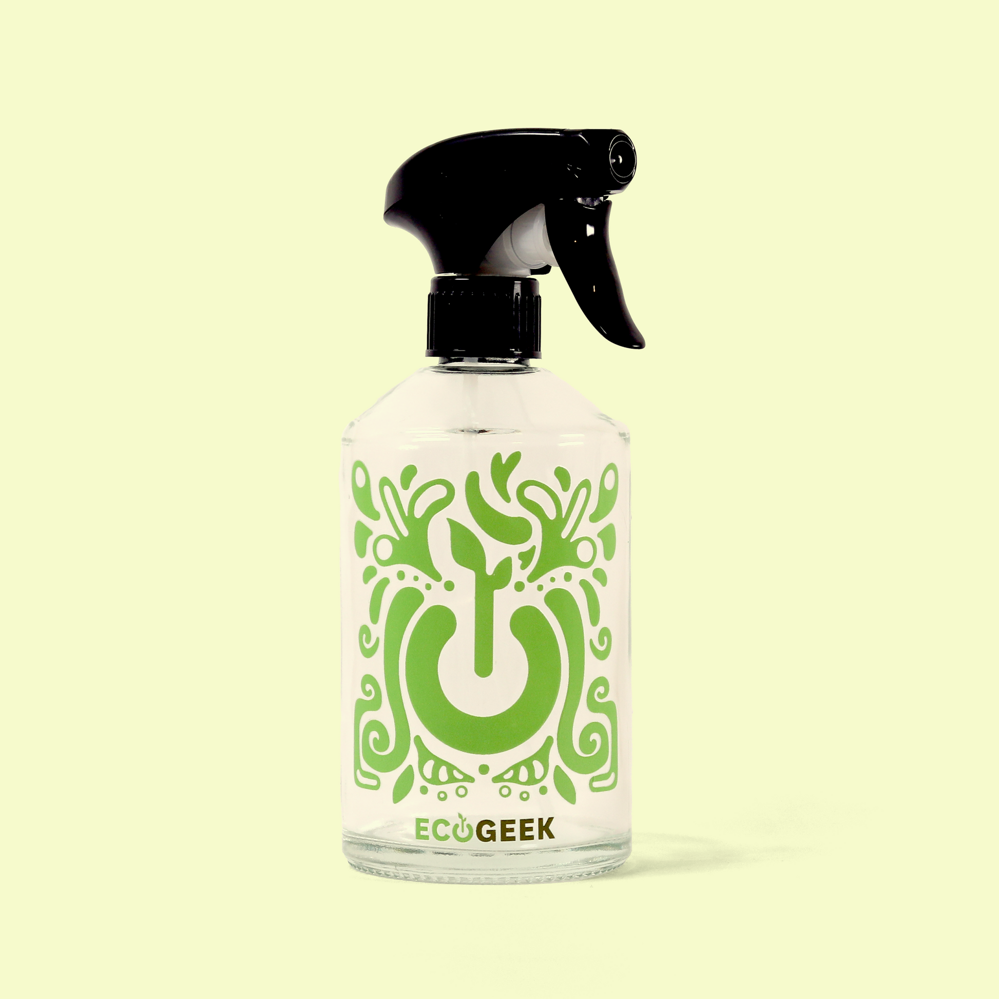 A clear glass spray bottle with a black trigger sprayer top featuring the ECOGEEK logo and decorative green power button design. The bottle has an ornate green pattern surrounding a power button symbol, displayed against a pale yellow background. Reusable glass spray bottle from EcoGeek a Good Store product.