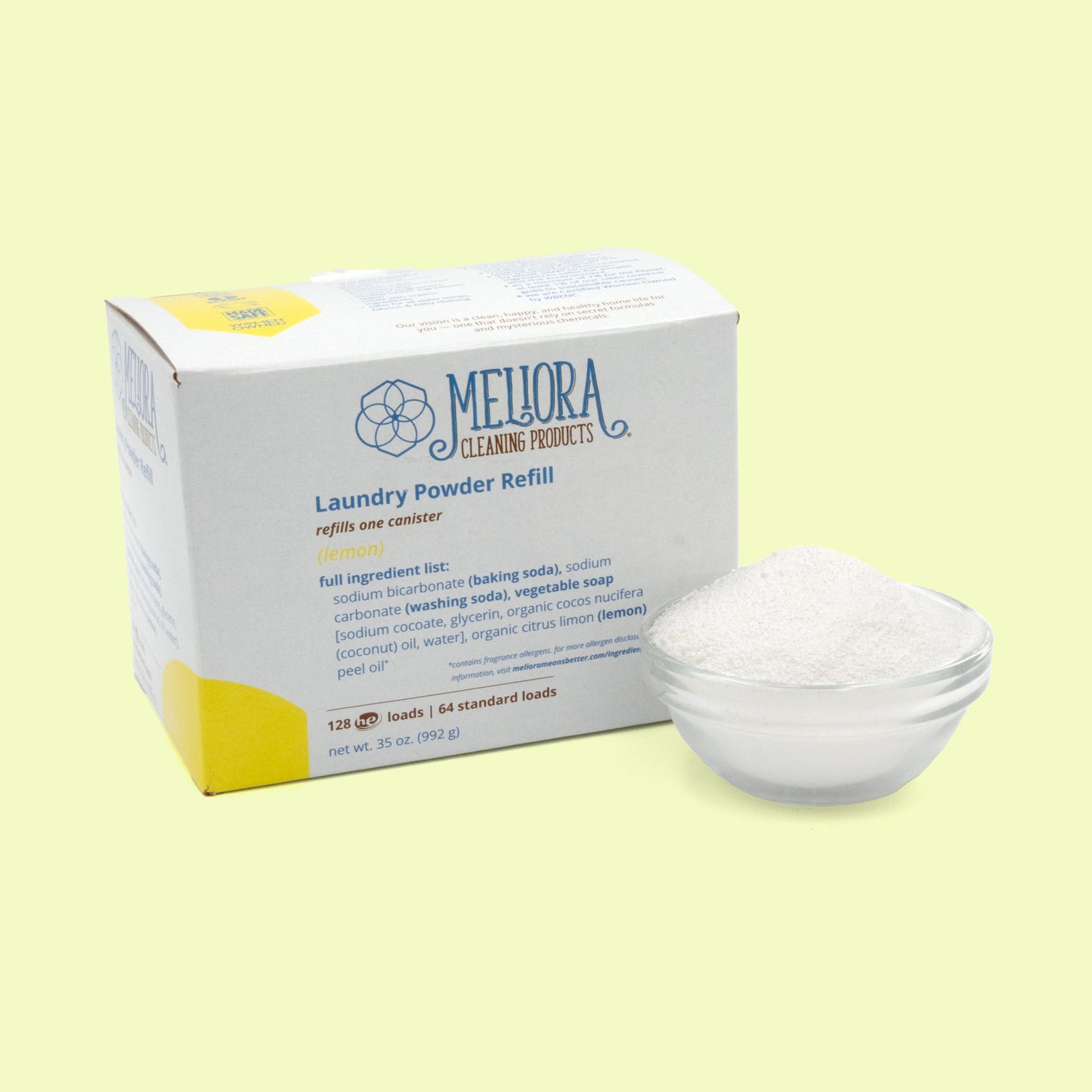 A white cardboard box of Meliora Cleaning Products Laundry Powder Refill in lemon scent, with yellow accent coloring and a geometric flower logo. Next to it is a clear glass bowl filled with white powdered laundry detergent. The box shows ingredient information and indicates it refills one canister with 128 HE loads or 64 standard loads, net weight 35 oz