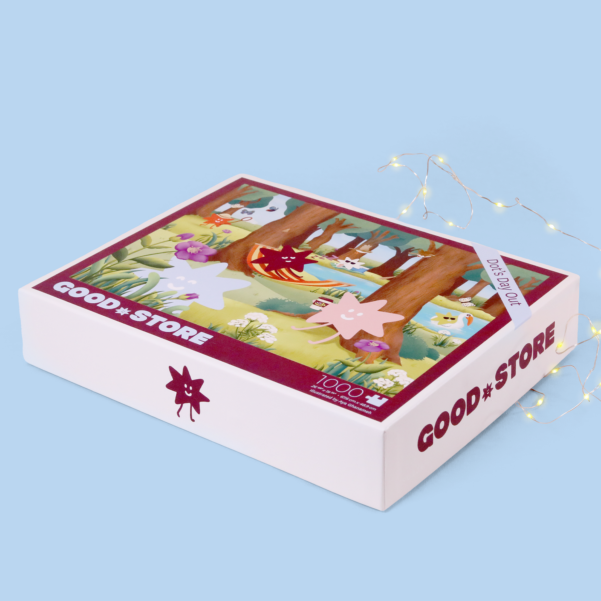 The same "Good Store" puzzle box titled "Dot's Day Out" shown open with loose puzzle pieces visible in the bottom half. The box lid displays the colorful woodland illustration featuring star characters, trees, and flowers. The scene is photographed against a light blue background with decorative fairy lights.