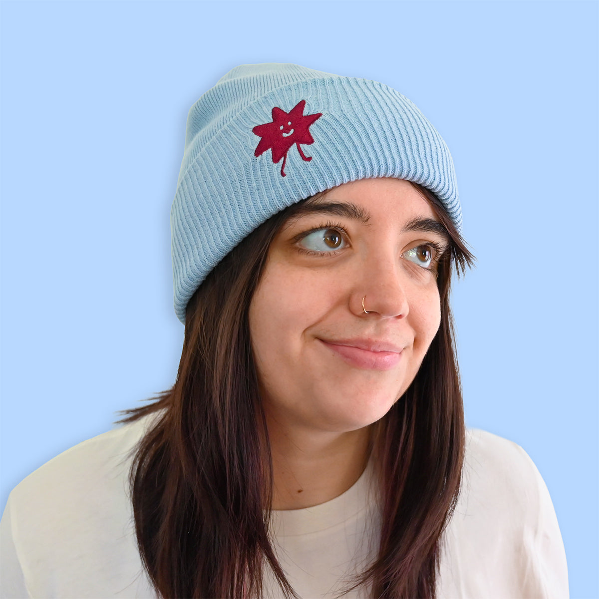 Person wearing a light blue beanie with a red star design against a light blue background