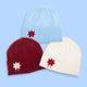 Three beanies in plum, blue, and cream with embroidered designs on a light blue background