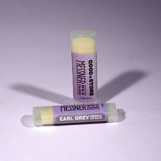 Two lip balm sticks with purple packaging on a light purple background