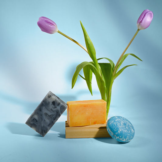 Three bars of soap with a vase of tulips on a light blue background