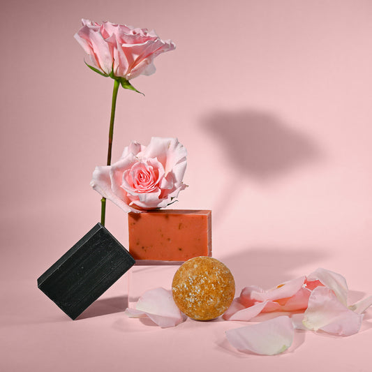 Shampoo bar, soap, and flowers on a pink background