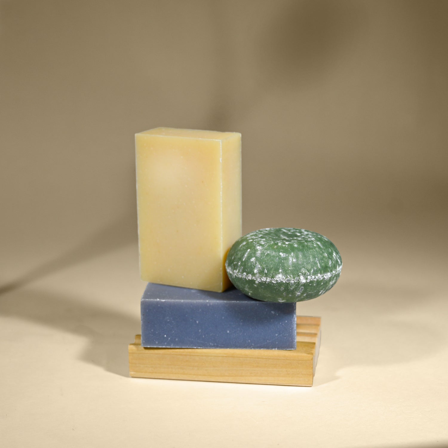 Three different types of soap on a beige surface with a neutral background