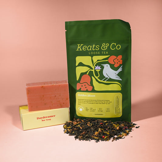 Green tea packaging with loose tea leaves and soap on a pink background