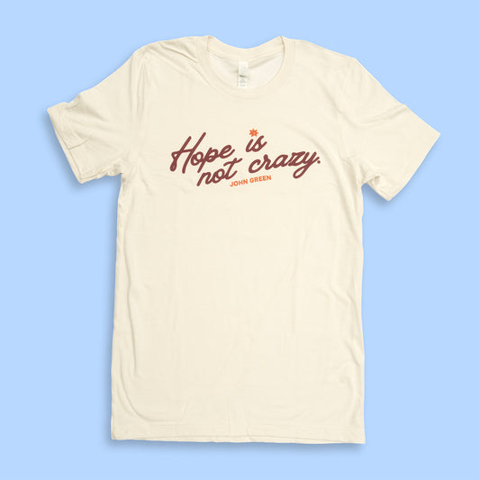 Beige t-shirt with 'Hope is crazy not crazy' text on a light blue background