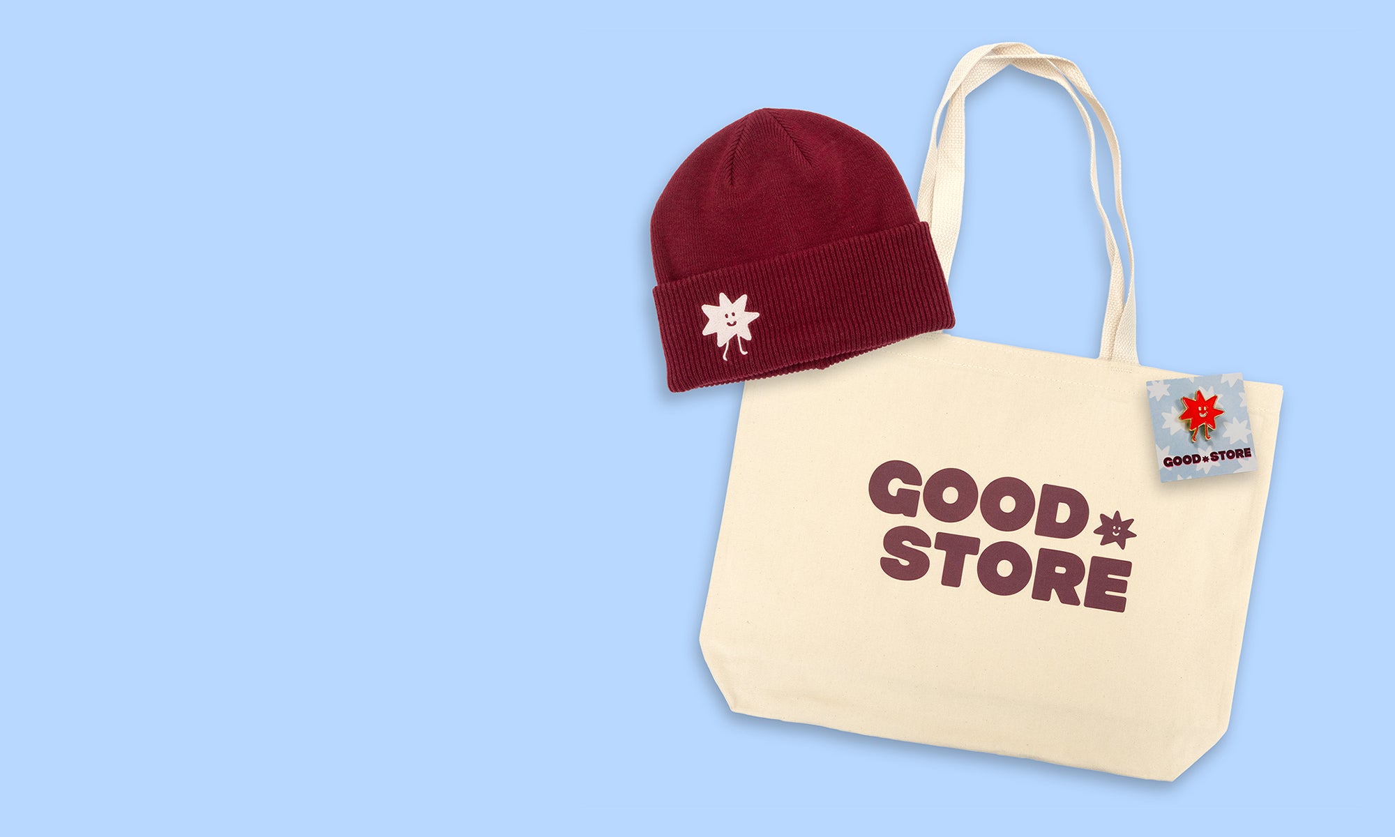 Beige tote bag with 'GOOD STORE' text and red beanie on a light blue background