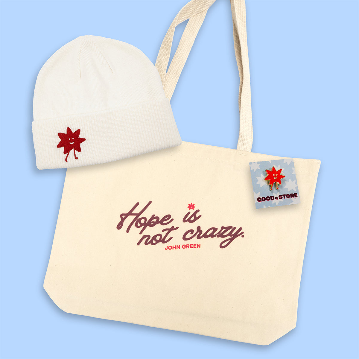 Tote bag with 'Hope is not crazy' quote, beanie, and small enamel pin on a light blue background