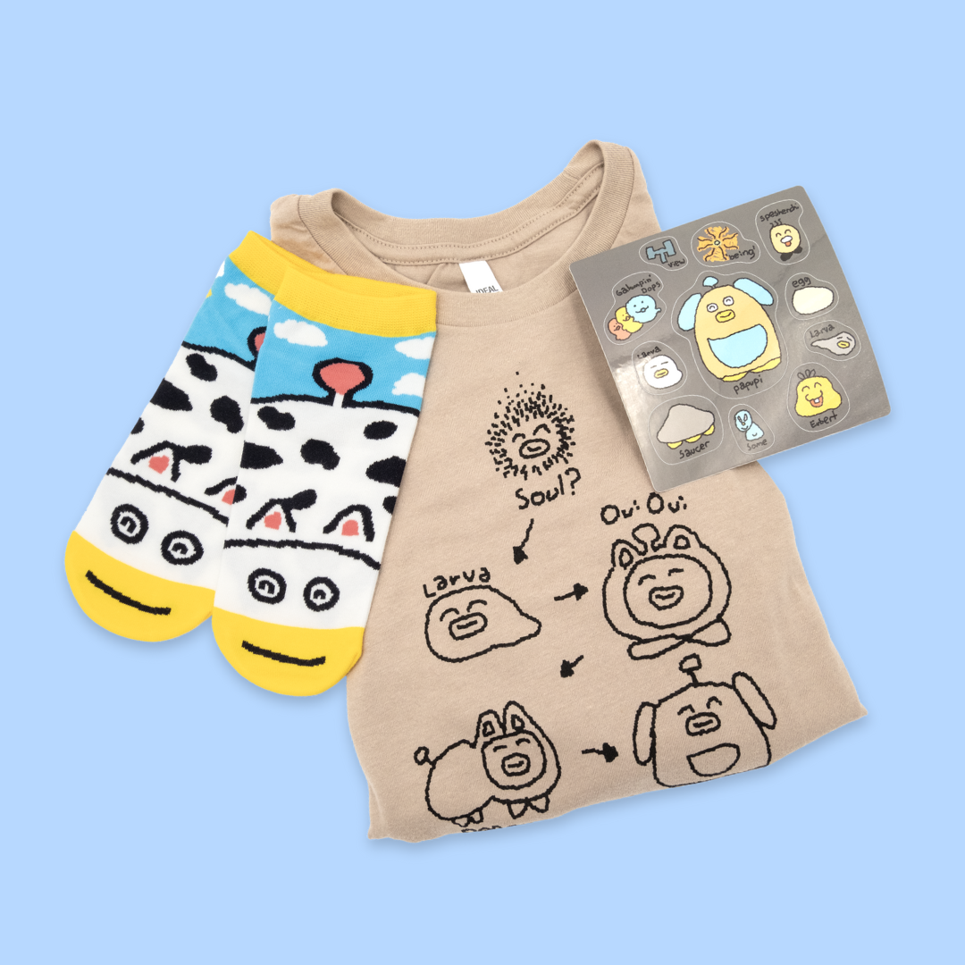 A tan crop top, cow-patterned socks, and gray sticker sheet on a light blue background. The crop top shows a cute character evolution cycle with arrows connecting "Soul," "Larva," "Ow Ow," "Puppy," and "Papaw." The socks feature white bodies with black cow spots, blue sky sections with clouds, yellow accents, and cartoon cow faces. The sticker sheet displays the same kawaii-style characters plus additional cute creatures, all labeled with names.