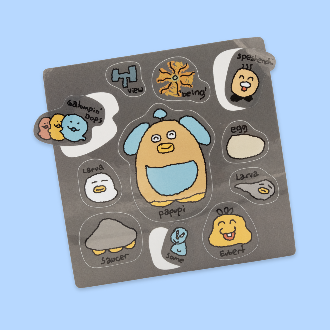 A gray sticker sheet on a light blue background featuring cute cartoon characters with their names. The central character is "Papupi," a large orange and blue dog-like creature with a happy expression. Surrounding it are smaller stickers including: "Galvanpi Pops" (three colorful round characters), "H View" (a blue castle-like shape), "Being" (an orange flower or sun design), "Speakendi" (a smiling face with black hair), "Egg" (a white oval), "Larva" (white blob-like characters), "Saucer" (a gray UFO shape)