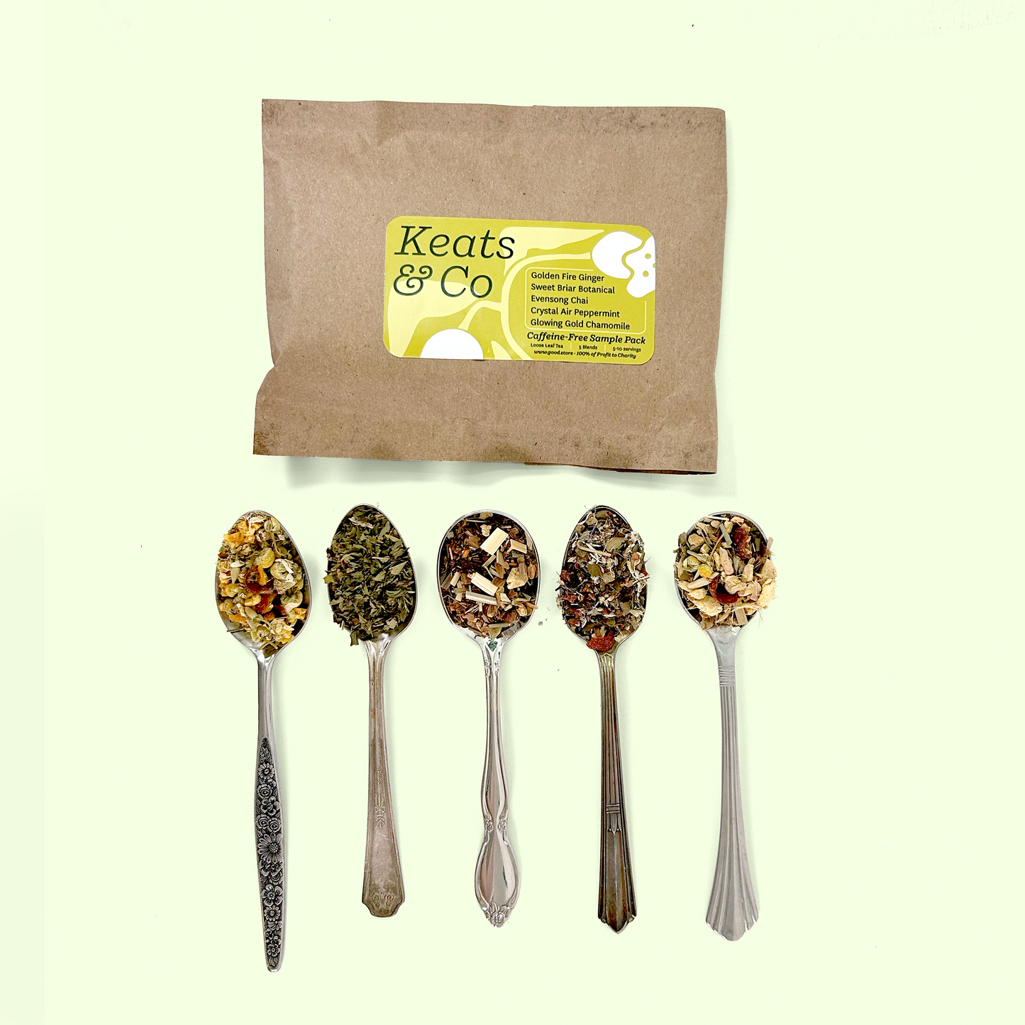 A Keats & Co tea sample pack in brown kraft paper with a yellow label reading 'Caffeine-Free Sample Pack' listing Golden Fire Ginger, Sweet Briar Botanical, Evensong Chai, Crystal Air Peppermint, and Glowing Gold Chamomile. Below are five ornate silver spoons displaying the herbal tea blends, which include colorful ingredients like dried flowers, herbs, and spices in various natural tones from golden yellow to deep brown.