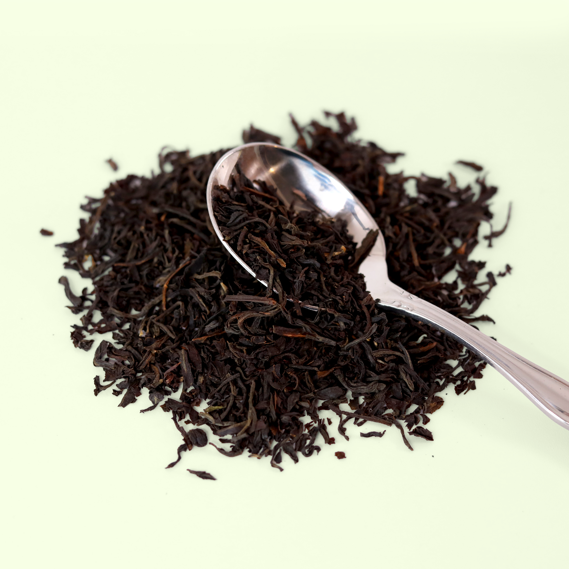  A close-up view of a pile of dried Bright Star Breakfast Blend tea leaves. A metal spoon is visible, scooping up some of the tea blend. A Good Store product.