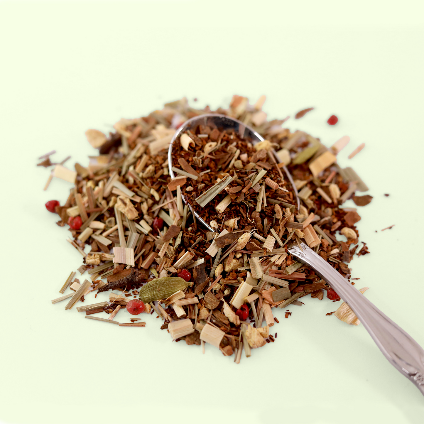 A close-up view of a pile of dried Evensong Chai tea leaves. A metal spoon is visible, scooping up some of the tea blend. A Good Store product.