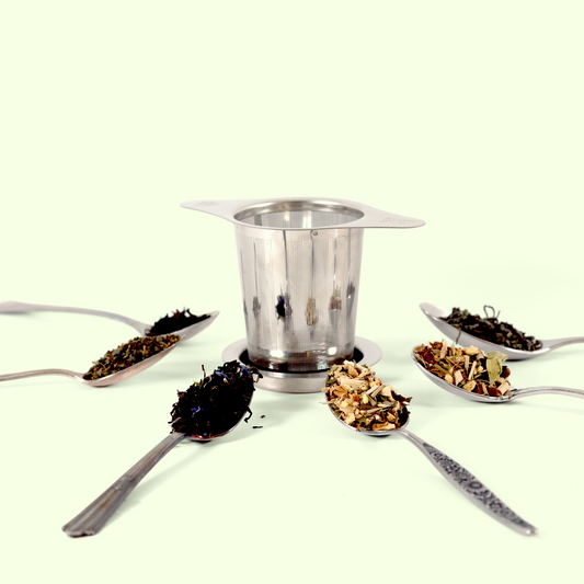 An image of a tea infuser in the center surrounded by spoons filled with various loose leaf teas. This image provides a top-down view, clearly showing the different tea types and the mesh basket of the strainer sitting on its lid. Keats & Co - Good Store. 