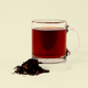 A clear glass mug filled with brewed dark reddish-brown tea. In front of the mug is a small pile of loose leaf tea, showing the dry tea leaves and colorful additions before brewing. Keats & Co.