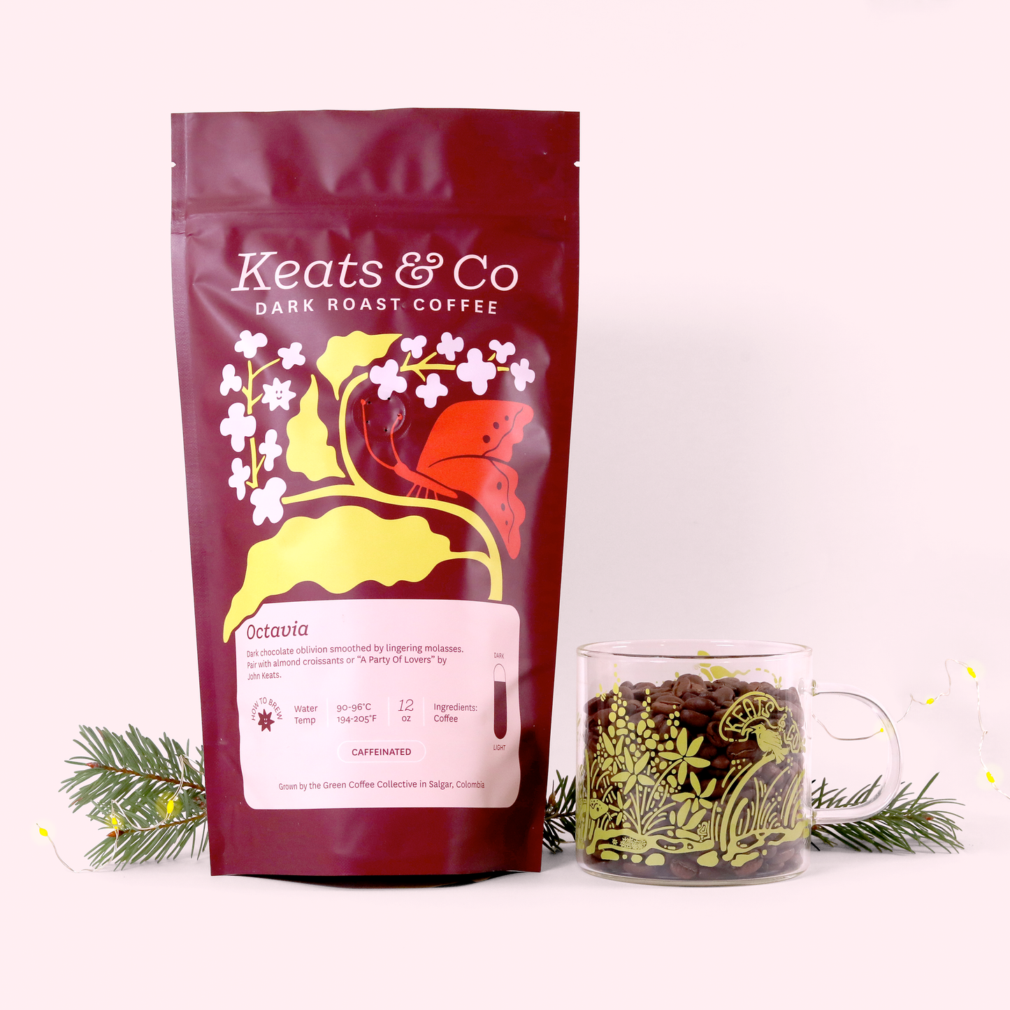 A product photo showing a burgundy Keats & Co coffee bag of 'Octavia' dark roast next to a matching decorated glass mug filled with coffee beans. Both items are arranged with pine branches on a white background. The bag features yellow and orange decorative elements including flowers and a butterfly.