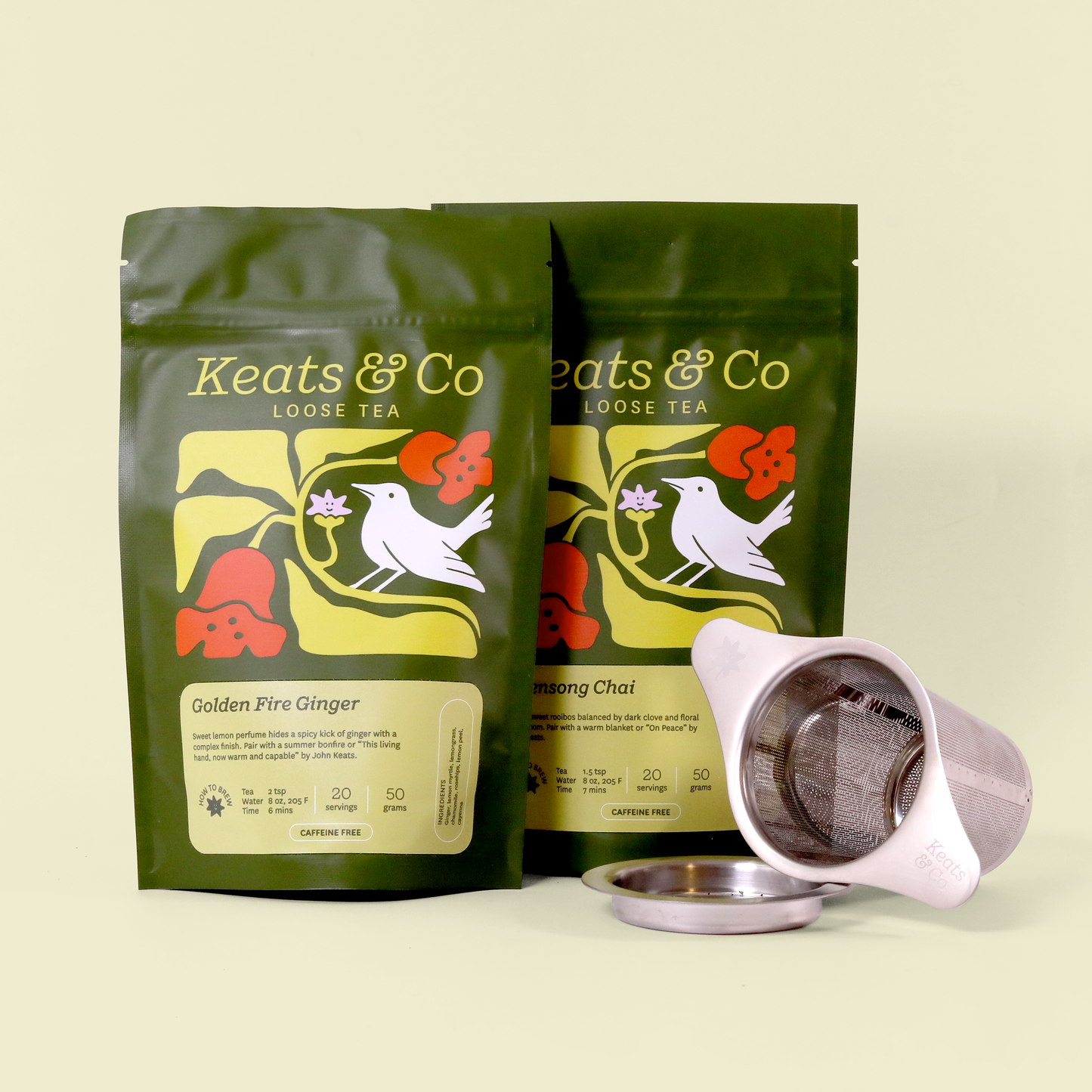 Product photo of two green Keats & Co loose tea packages with a white bird and floral design, shown with a silver tea strainer and its base. The packages show "Golden Fire Ginger" and "Evensong Chai" varieties against a cream background. Both packages are marked as caffeine-free and include brewing instructions.