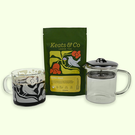 Tea set with mug, tea bag, and glass teapot on a white background