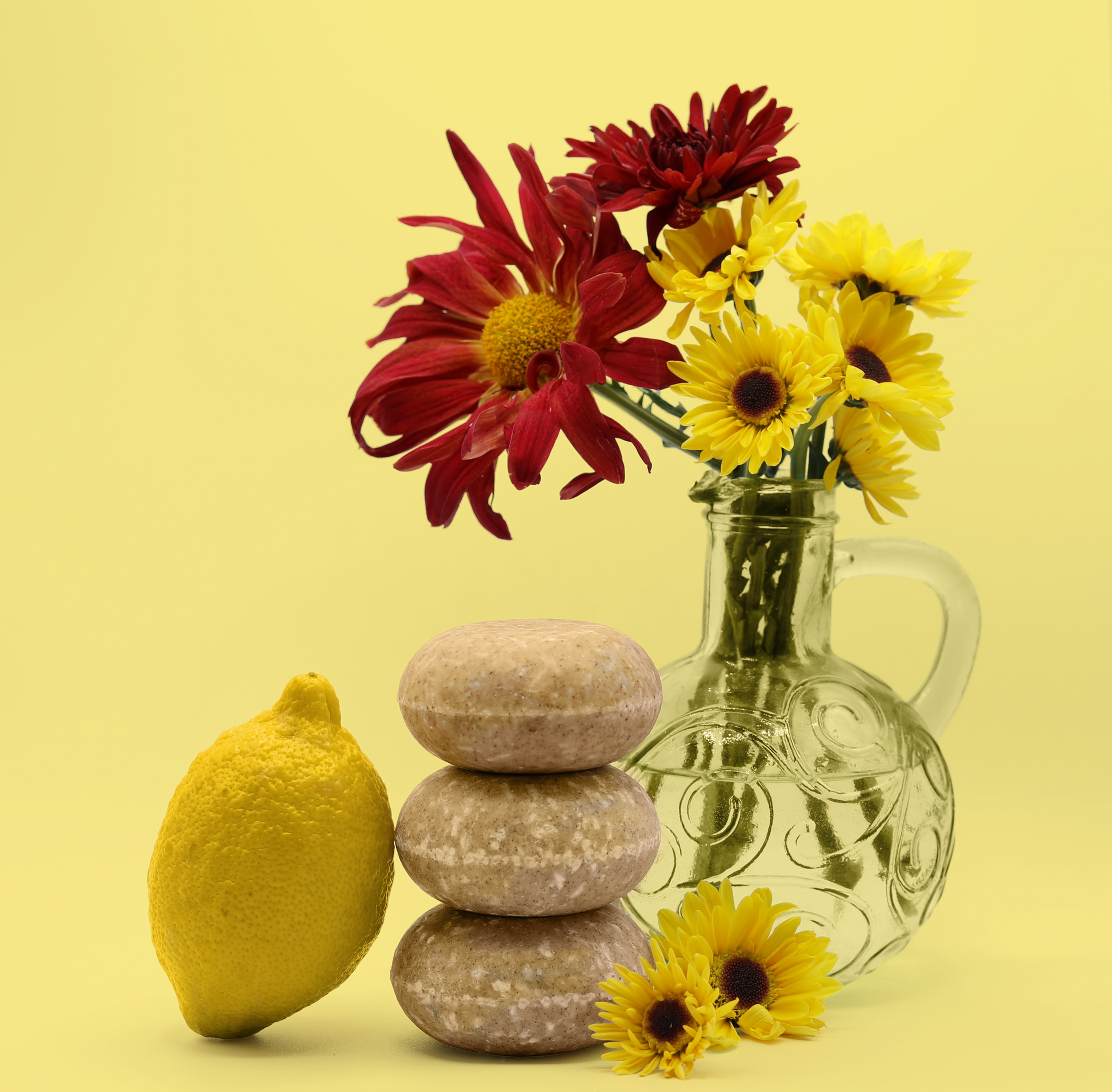 Three bars of the Blossom shampoo bars from Sun Basin Soap are stacked on top of each other. On one side is a lemon and the other is bouquet of red and yellow flowers. A Good Store subscription product.