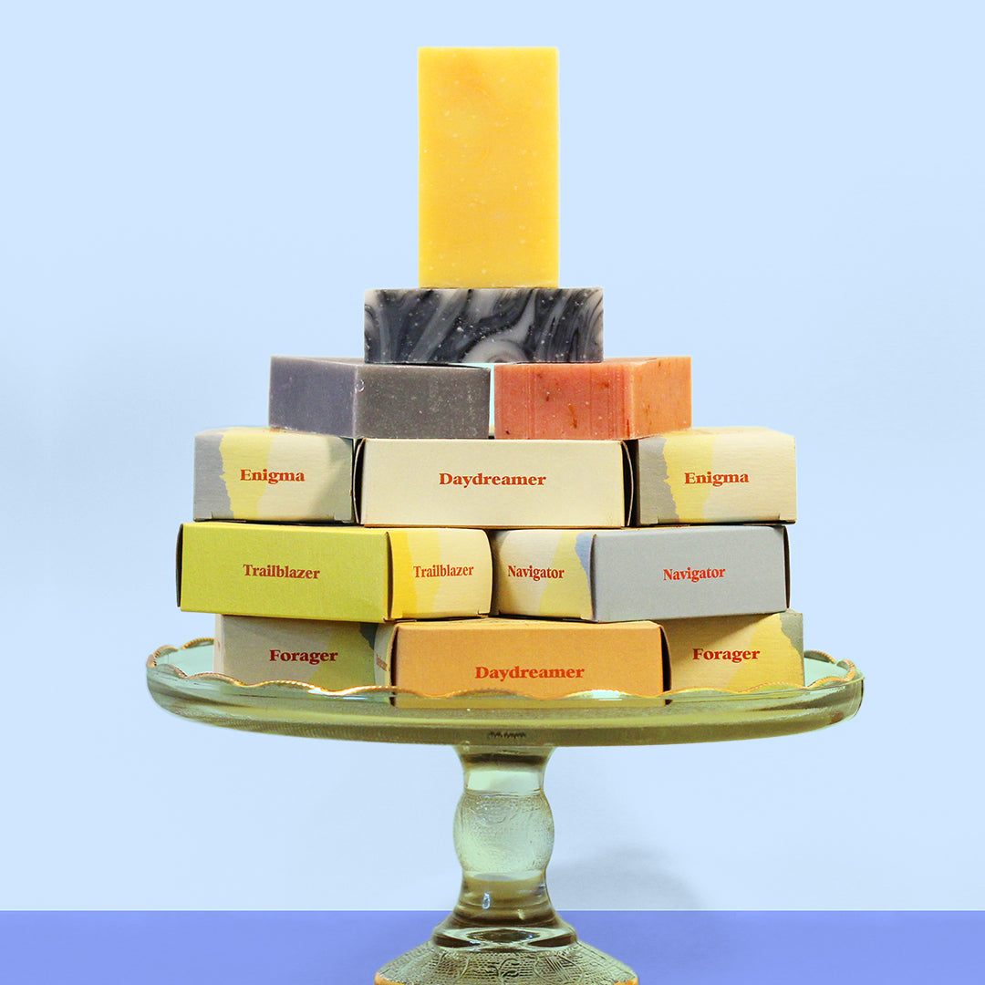 Stack of soap bars with visible labels on a decorative stand against a light blue background