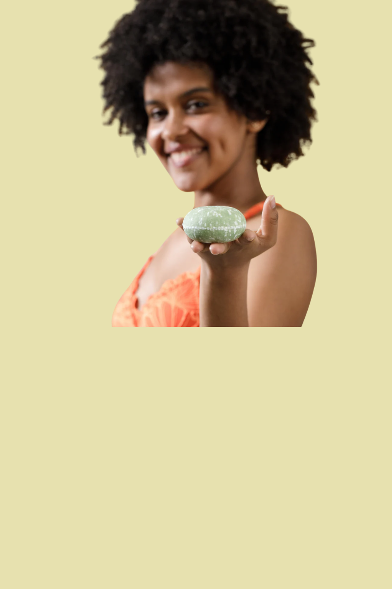 Image of a person holding a solid green shampoo bar from Sun Basin Soap in front of a green background