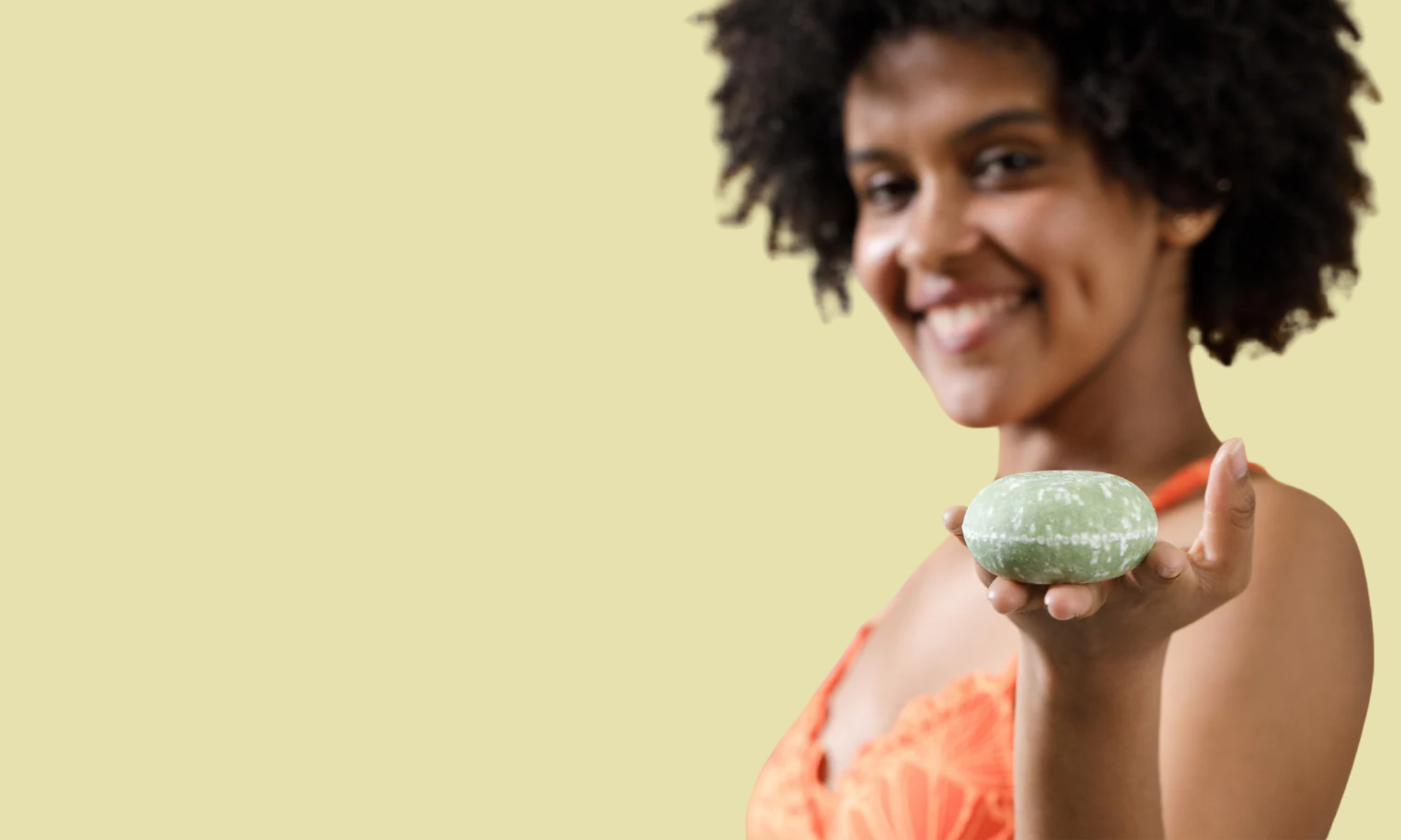 Image of a woman holding a solid green shampoo bar from Sun Basin Soap in front of a green background