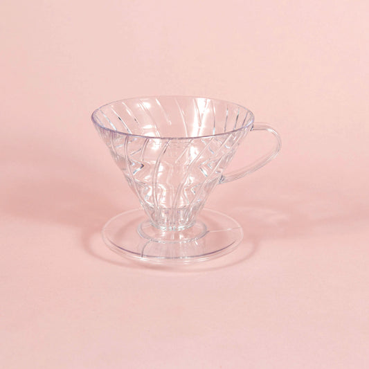 Clear, plastic coffee pour over sitting in the middle of a light pink background. Available through the Awesome Coffee Club. A Good Store subscription product.